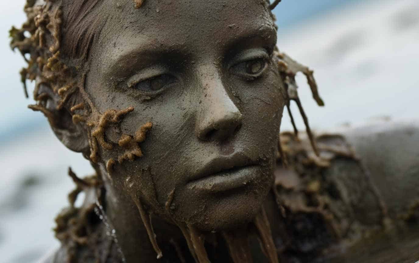 A young woman turned almost into a stone statue watching the sea.